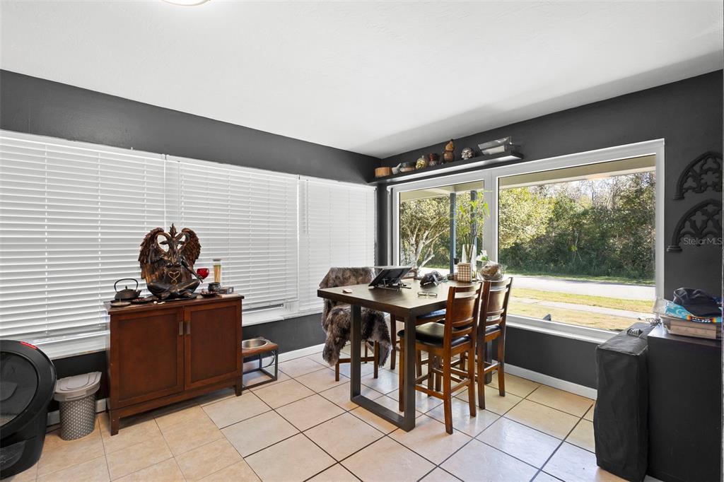 A dining area with dark gray walls, tile flooring, a wooden table, and large windows — 1552 ZINNIA DRIVE, DELTONA, FL