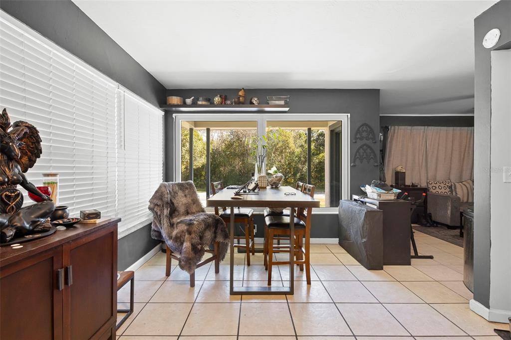 A dining area with tile floors, dark gray walls, and a window overlooking trees — 1552 ZINNIA DRIVE, DELTONA, FL