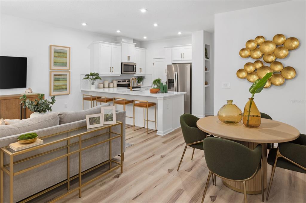 An open-concept kitchen and dining area features white cabinetry, a breakfast bar, and wood flooring — 233 SPINDLE PALM COVE, WINTER SPRINGS, FL