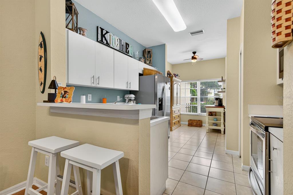 A kitchen features white cabinets, a breakfast bar with stools, and tile flooring — 10951 WINTER CREST DRIVE, RIVERVIEW, FL