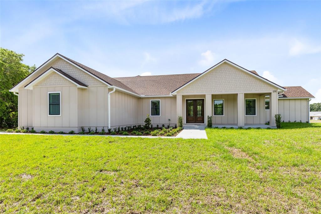 A single-story house with beige vertical siding, a covered front porch, and a brown roof — 1290 WHITMAN LANE, KENANSVILLE, FL