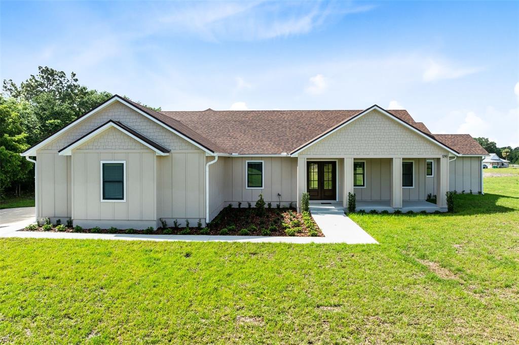A single-story house with tan board-and-batten siding and a brown shingled roof — 1290 WHITMAN LANE, KENANSVILLE, FL