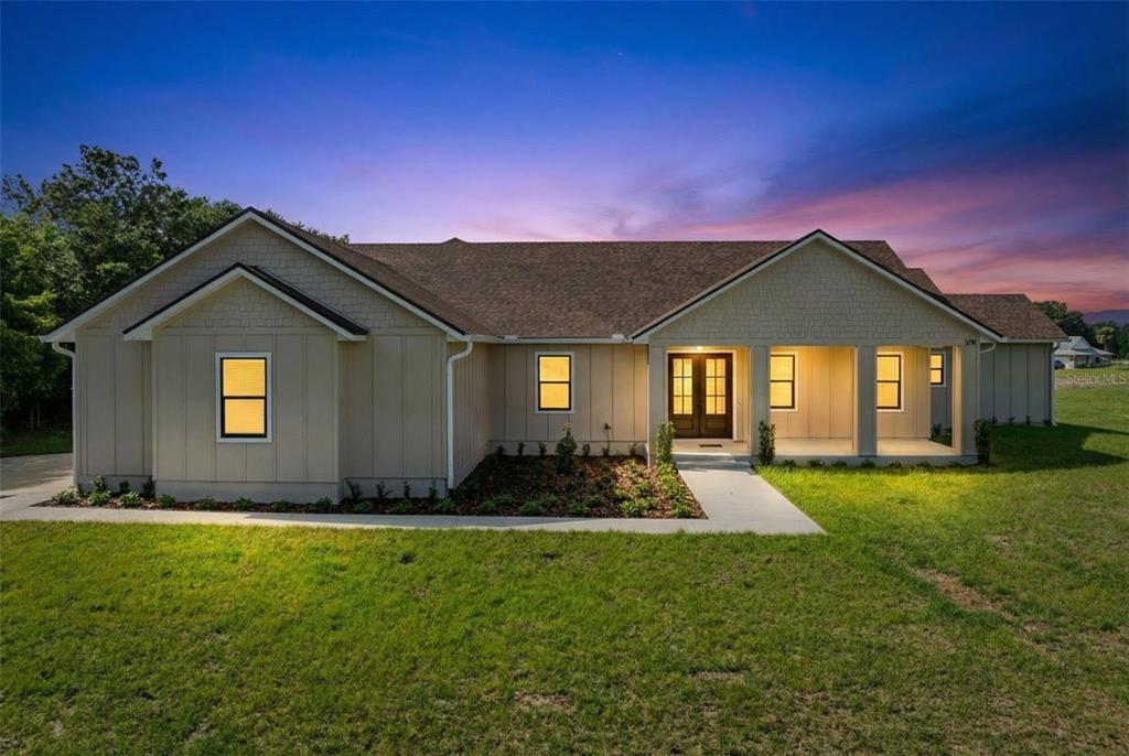 A single-story house with beige siding, a covered front porch, and a sunset sky — 1290 WHITMAN LANE, KENANSVILLE, FL