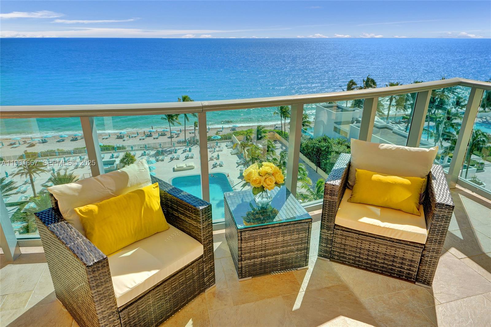 A balcony features two wicker chairs with yellow cushions and a glass-topped table overlooking the ocean — 2501 S Ocean Dr, Hollywood FL 33019, HOLLYWOOD, FL