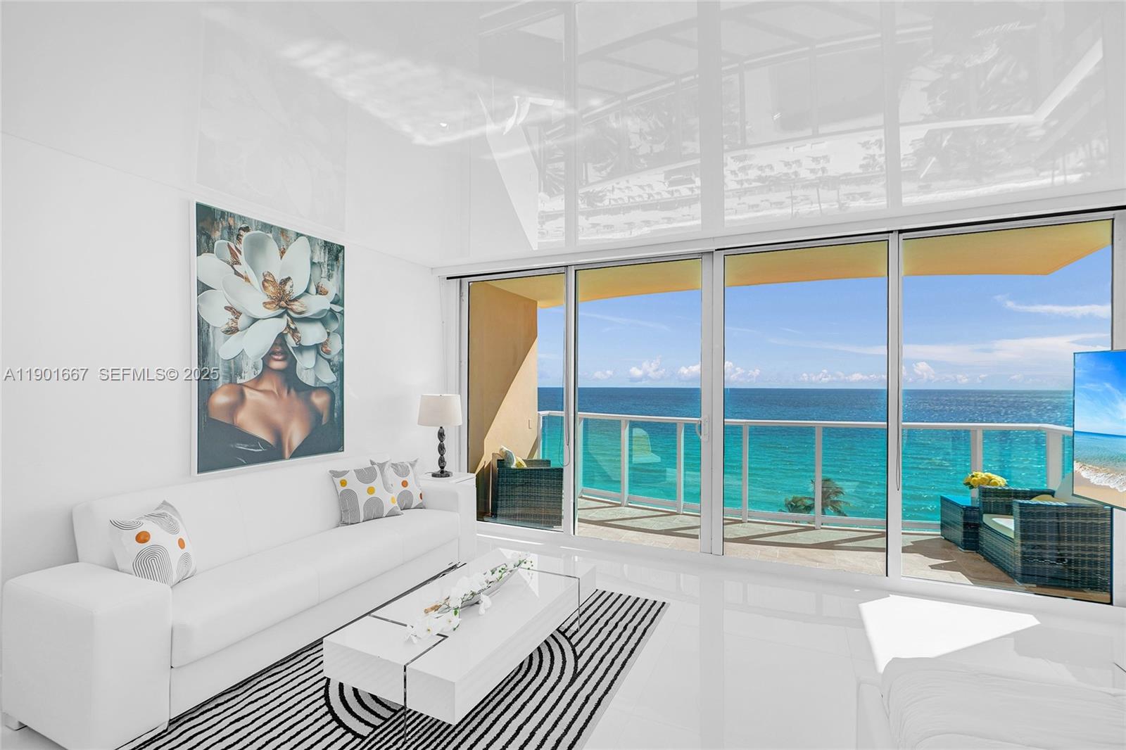A modern living room features white furniture, a striped rug, and floor-to-ceiling windows overlooking the ocean — 2501 S Ocean Dr, Hollywood FL 33019, HOLLYWOOD, FL