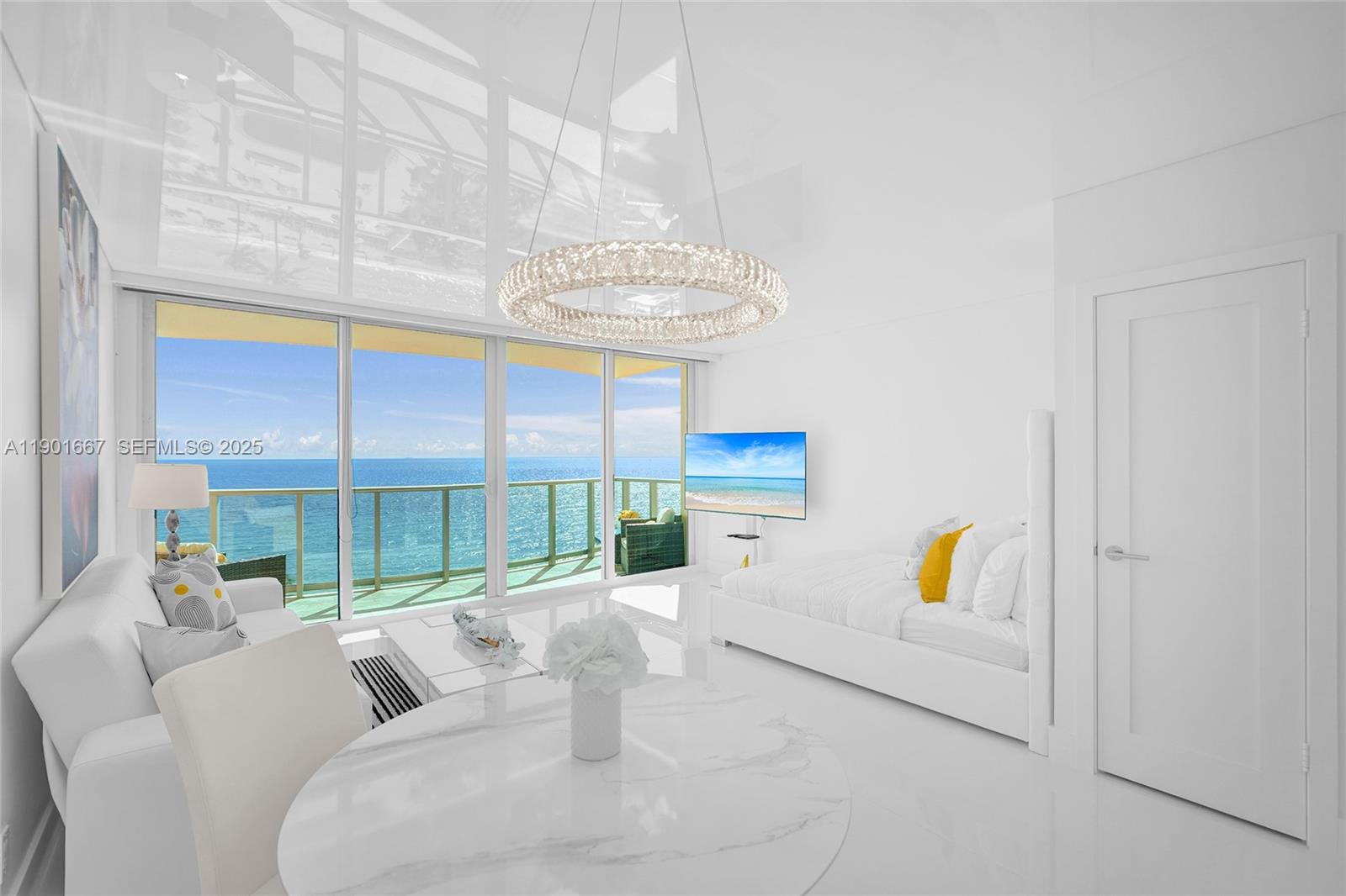 A bright, white-themed room features a circular chandelier, marble table, and floor-to-ceiling ocean views — 2501 S Ocean Dr, Hollywood FL 33019, HOLLYWOOD, FL