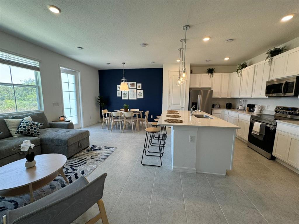 An open-concept kitchen and living area features white cabinetry, a large island, and blue accent wall — 661 LONGBOAT DRIVE, DAVENPORT, FL