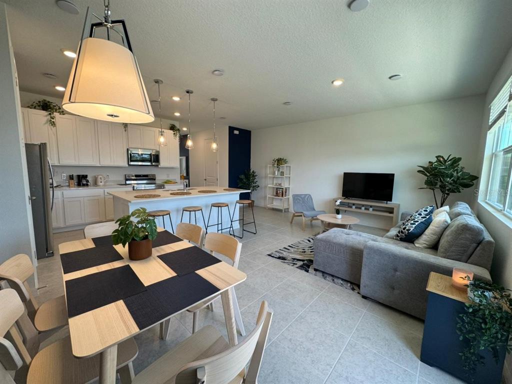 An open-concept living area features a kitchen with white cabinets, a dining table, and sofa — 661 LONGBOAT DRIVE, DAVENPORT, FL