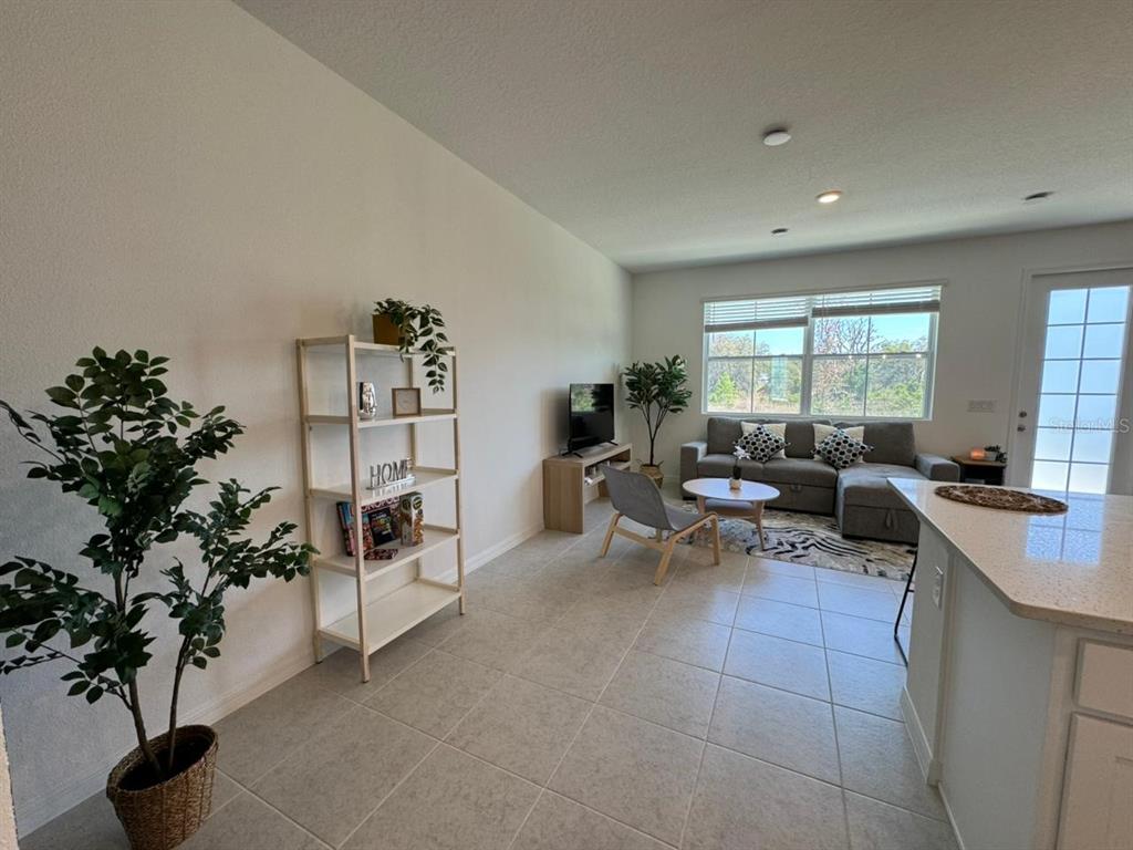 A living room features tile flooring, a bookshelf, a sectional sofa, and a glass door — 661 LONGBOAT DRIVE, DAVENPORT, FL