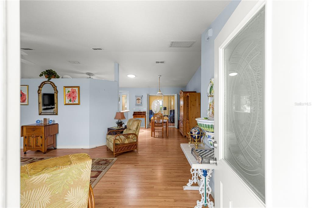 A view from a doorway into a living and dining area with wood-look flooring — 6046 SW 98 LOOP, OCALA, FL
