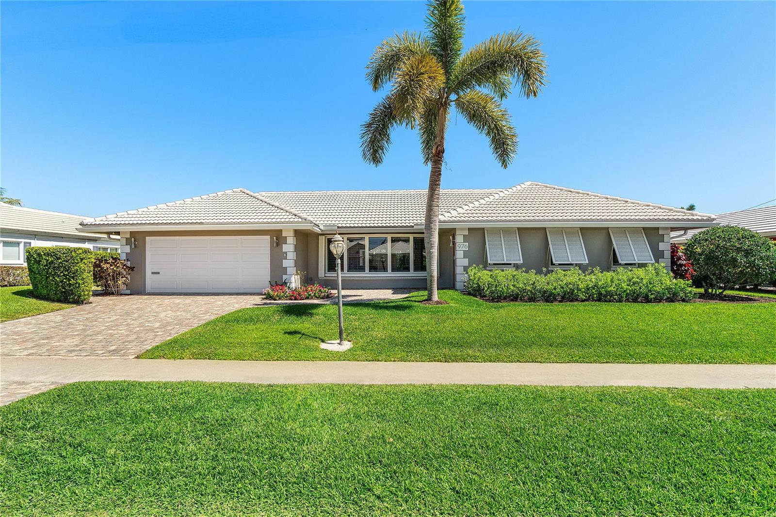 A single-story house with a white tile roof, a palm tree, and a paved driveway — 976 SW Mulberry Way, Boca Raton FL 33486, BOCA RATON, FL