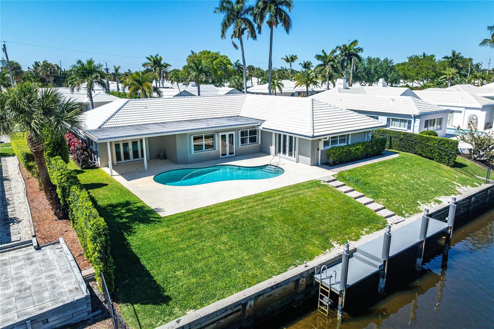 An aerial view of a house with a white roof, pool, lawn, and private dock — 976 SW Mulberry Way, Boca Raton FL 33486, BOCA RATON, FL