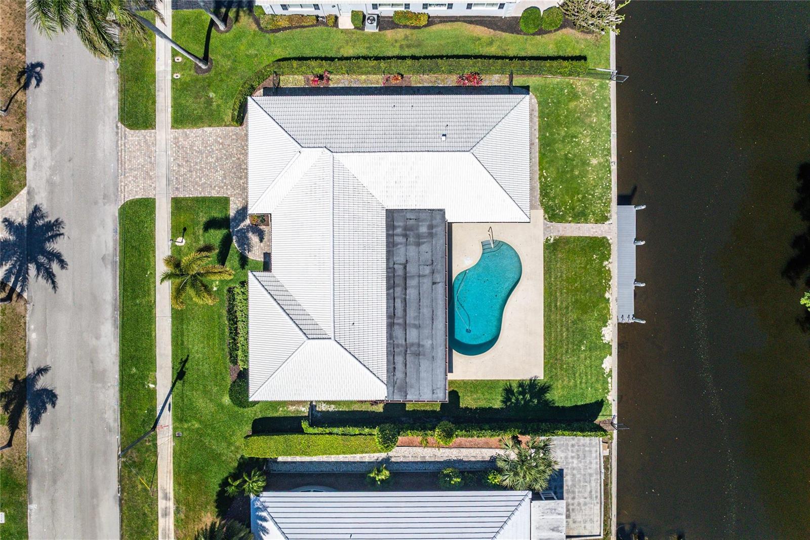 An aerial view shows a house with a white roof, a pool, and a canal dock — 976 SW Mulberry Way, Boca Raton FL 33486, BOCA RATON, FL