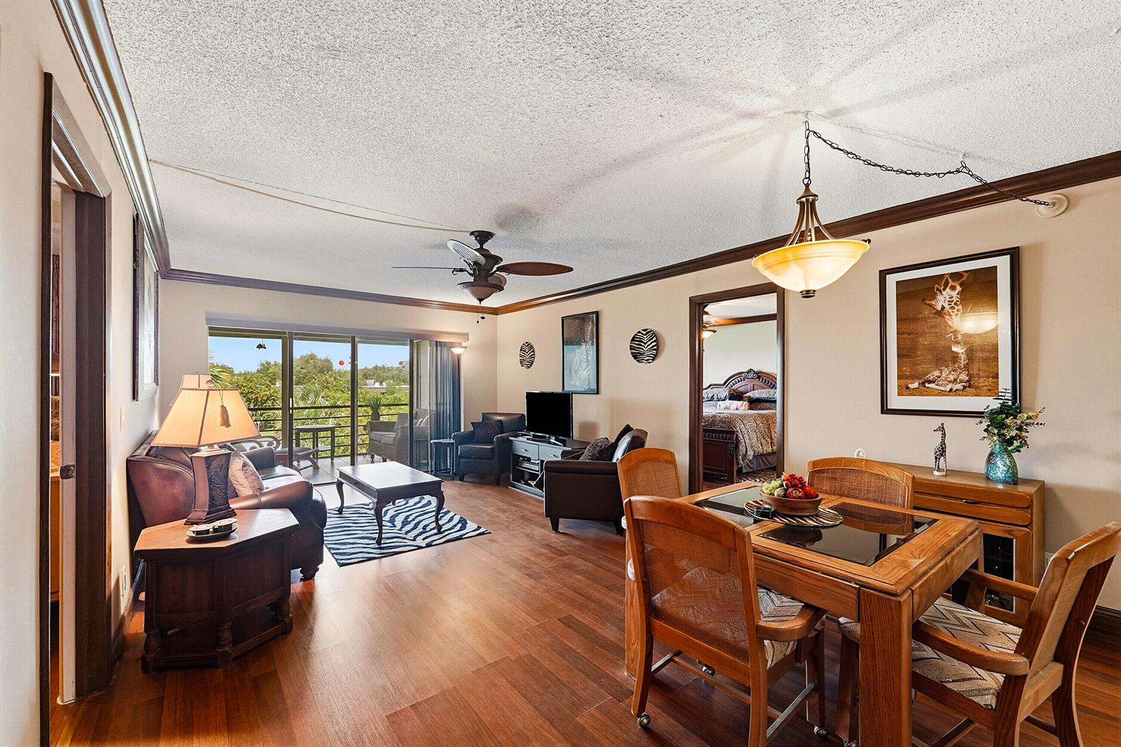 A living and dining area with wood-look flooring, a ceiling fan, and a balcony view — 9273 SW 8th Street # 321, Boca Raton FL 33428, BOCA RATON, FL