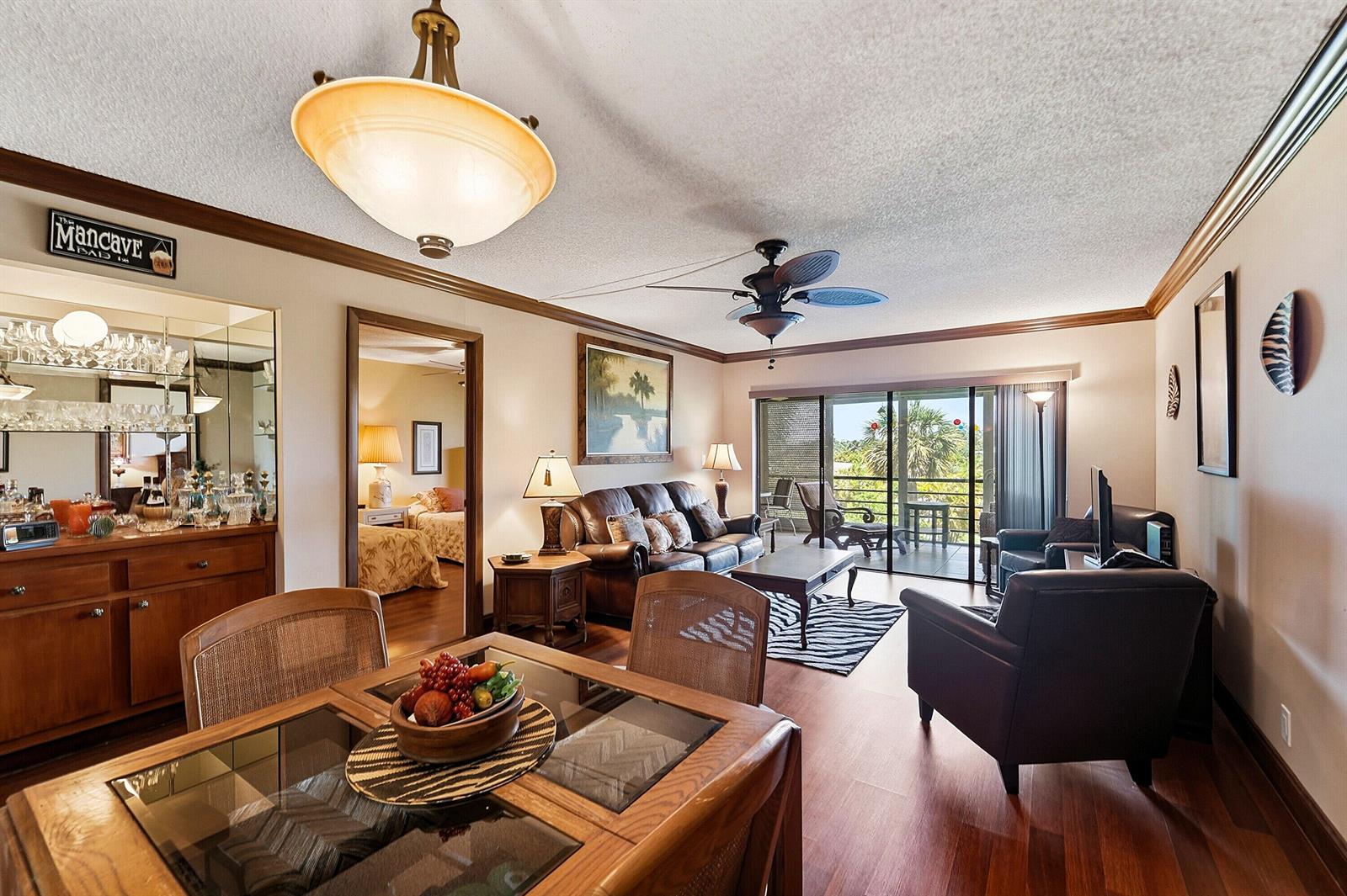 A living room and dining area with wood floors, leather furniture, and a balcony view — 9273 SW 8th Street # 321, Boca Raton FL 33428, BOCA RATON, FL