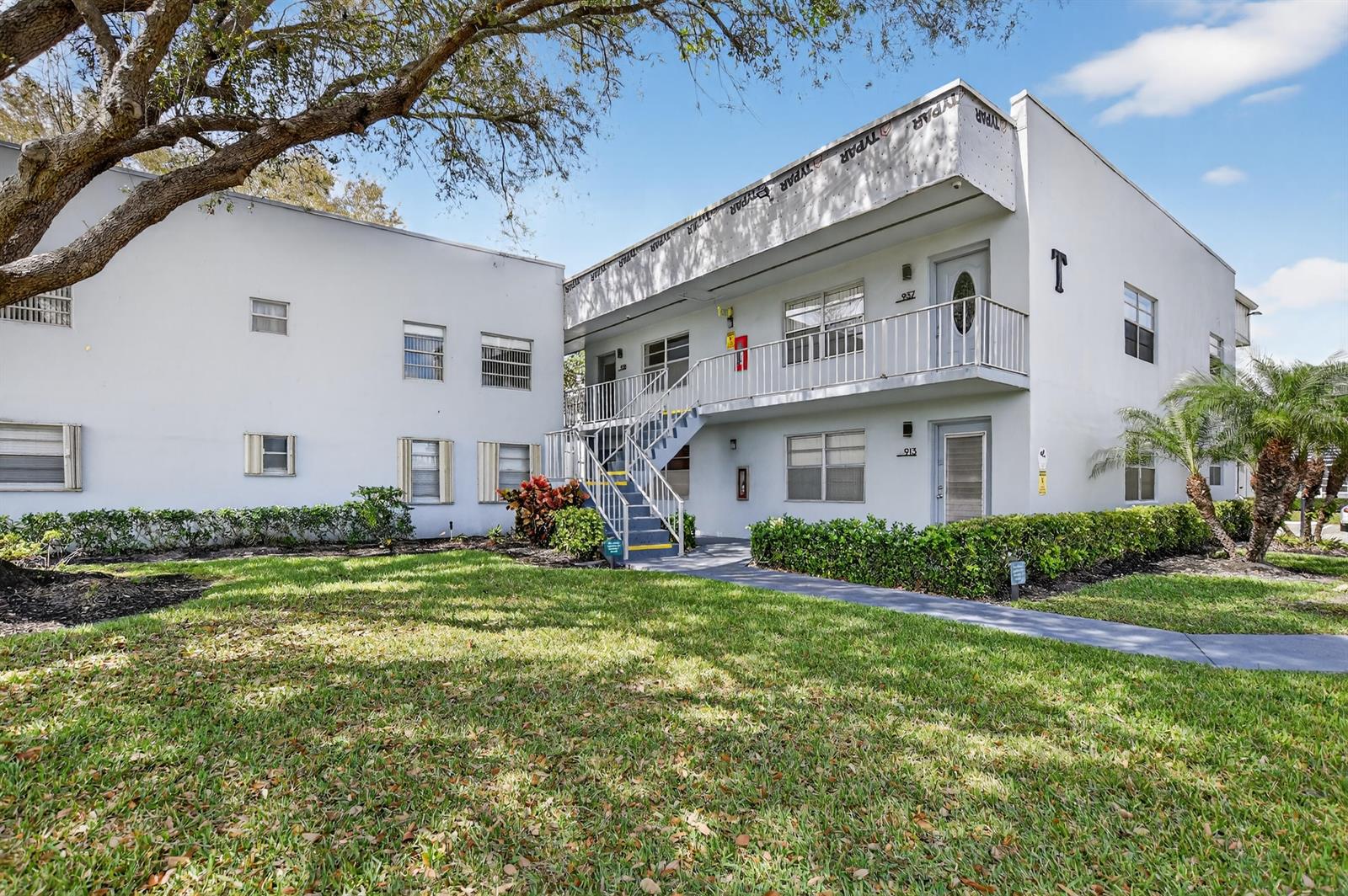 A two-story white apartment building features an exterior staircase and a grassy front lawn — 944 Normandy Trail # 944, Delray Beach FL 33484, DELRAY BEACH, FL