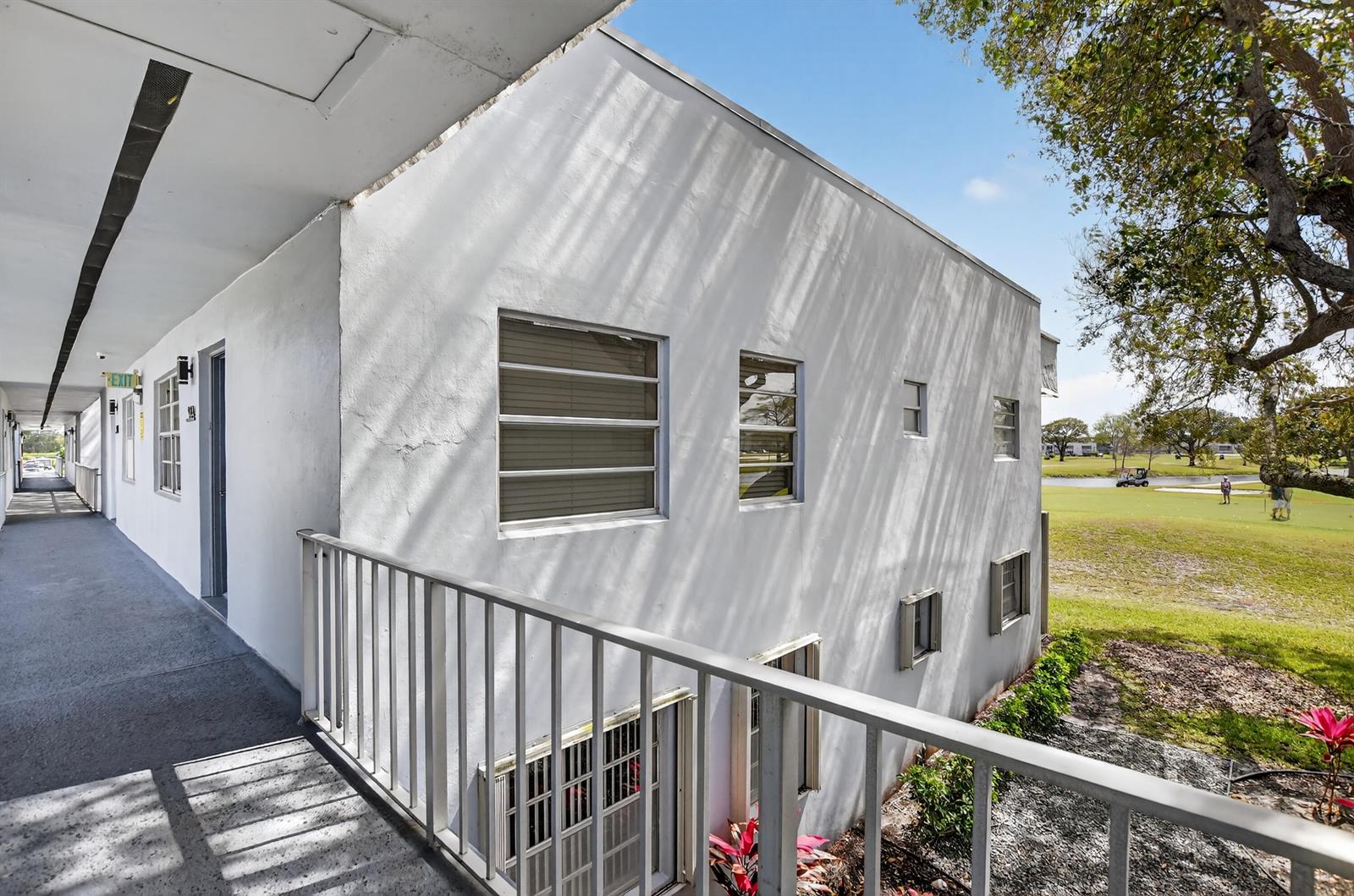 An exterior view of a white building with a walkway overlooking a golf course — 944 Normandy Trail # 944, Delray Beach FL 33484, DELRAY BEACH, FL