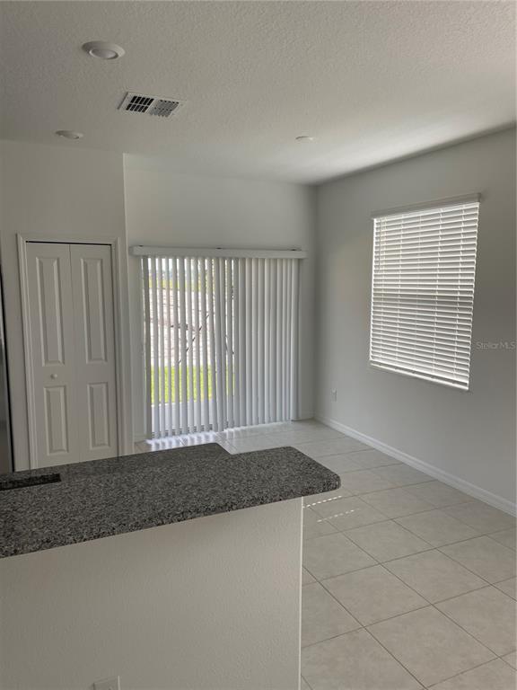 A dining area with tile flooring, a sliding glass door, and a granite-topped kitchen counter — 32077 POWDERPUFF MIMOSA, SAN ANTONIO, FL