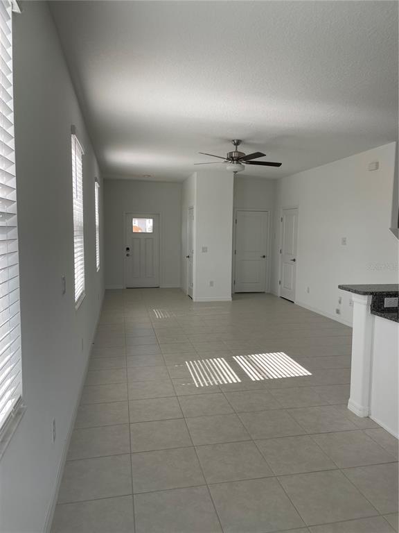 An interior view shows a tiled living area with white walls, a ceiling fan, and doors — 32077 POWDERPUFF MIMOSA, SAN ANTONIO, FL