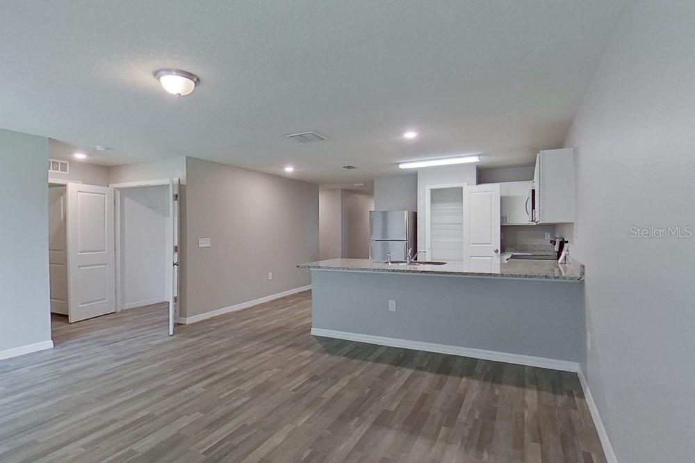 A kitchen with a granite breakfast bar opens into a living area with wood-look flooring — 2907 W CAMILO DRIVE, CITRUS SPRINGS, FL