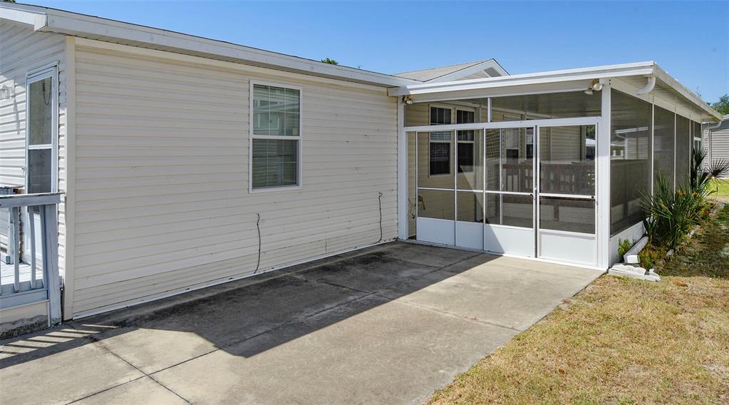 A side view of a manufactured home featuring a concrete patio and a screened-in porch — 11921 SALINA WAY, LEESBURG, FL