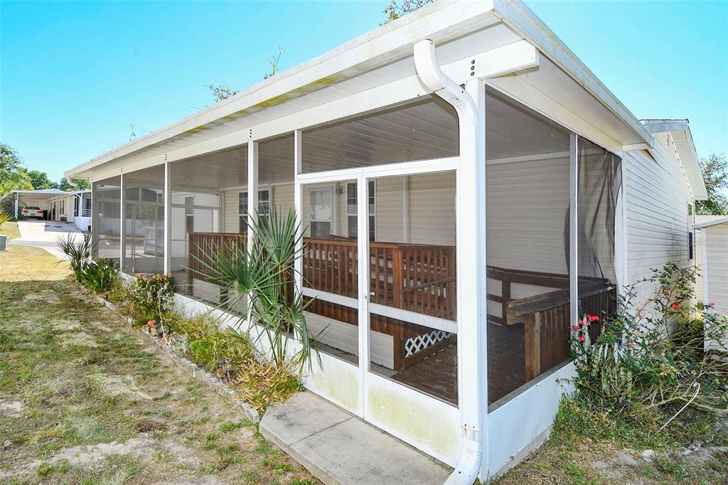 A screened-in porch with a wooden deck and white frame exterior on a sunny day — 11921 SALINA WAY, LEESBURG, FL