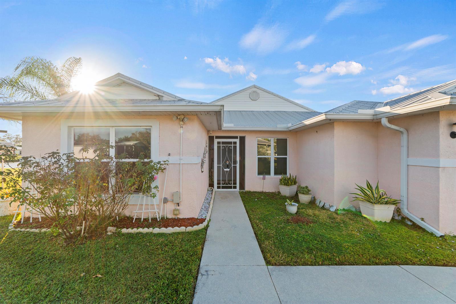 A light pink house with a metal roof and a concrete walkway to the entrance — 14191 Cisne Circle, Fort Pierce FL 34951, FORT PIERCE, FL