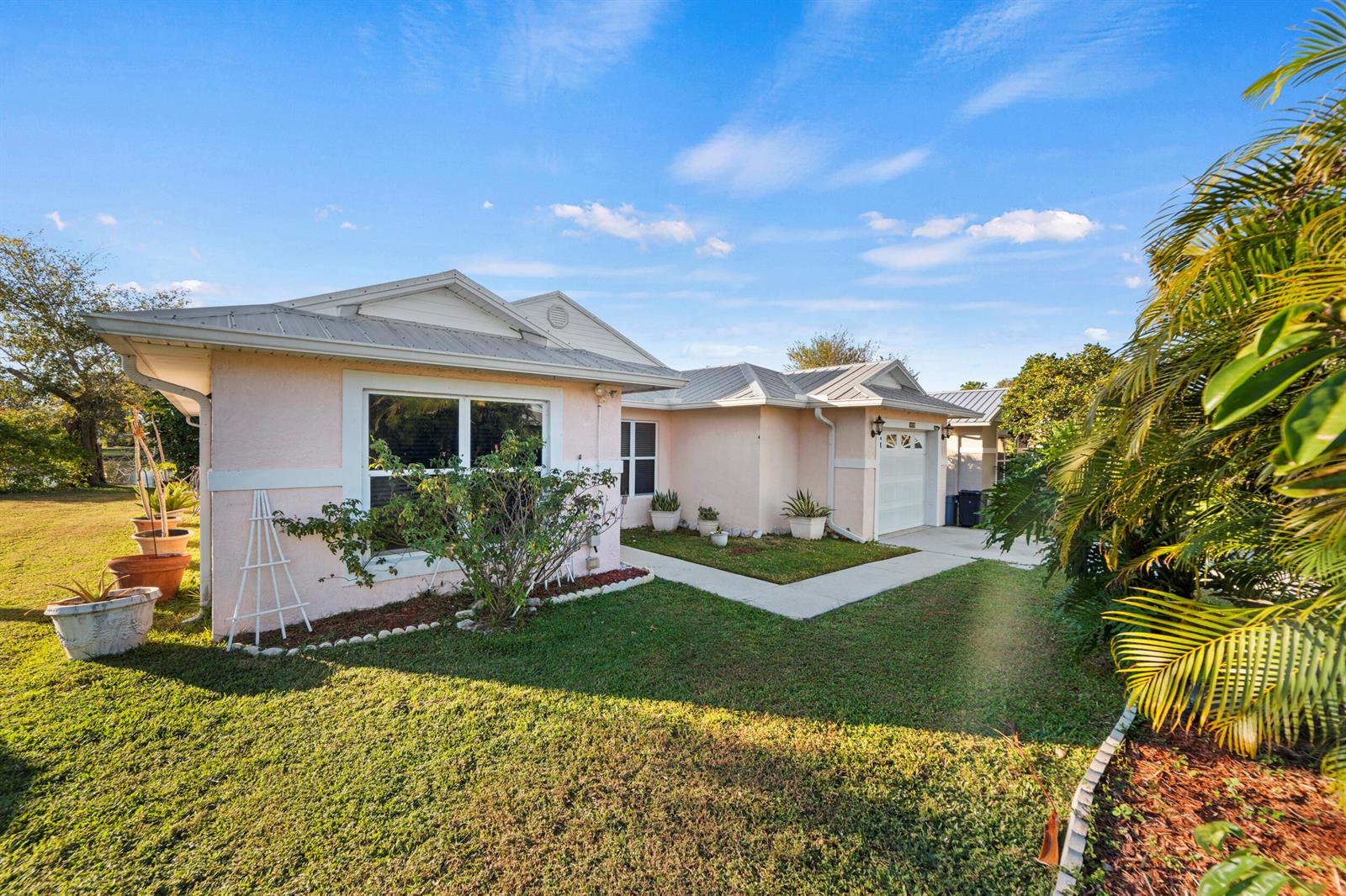 A light pink single-story house with a metal roof and a concrete walkway — 14191 Cisne Circle, Fort Pierce FL 34951, FORT PIERCE, FL