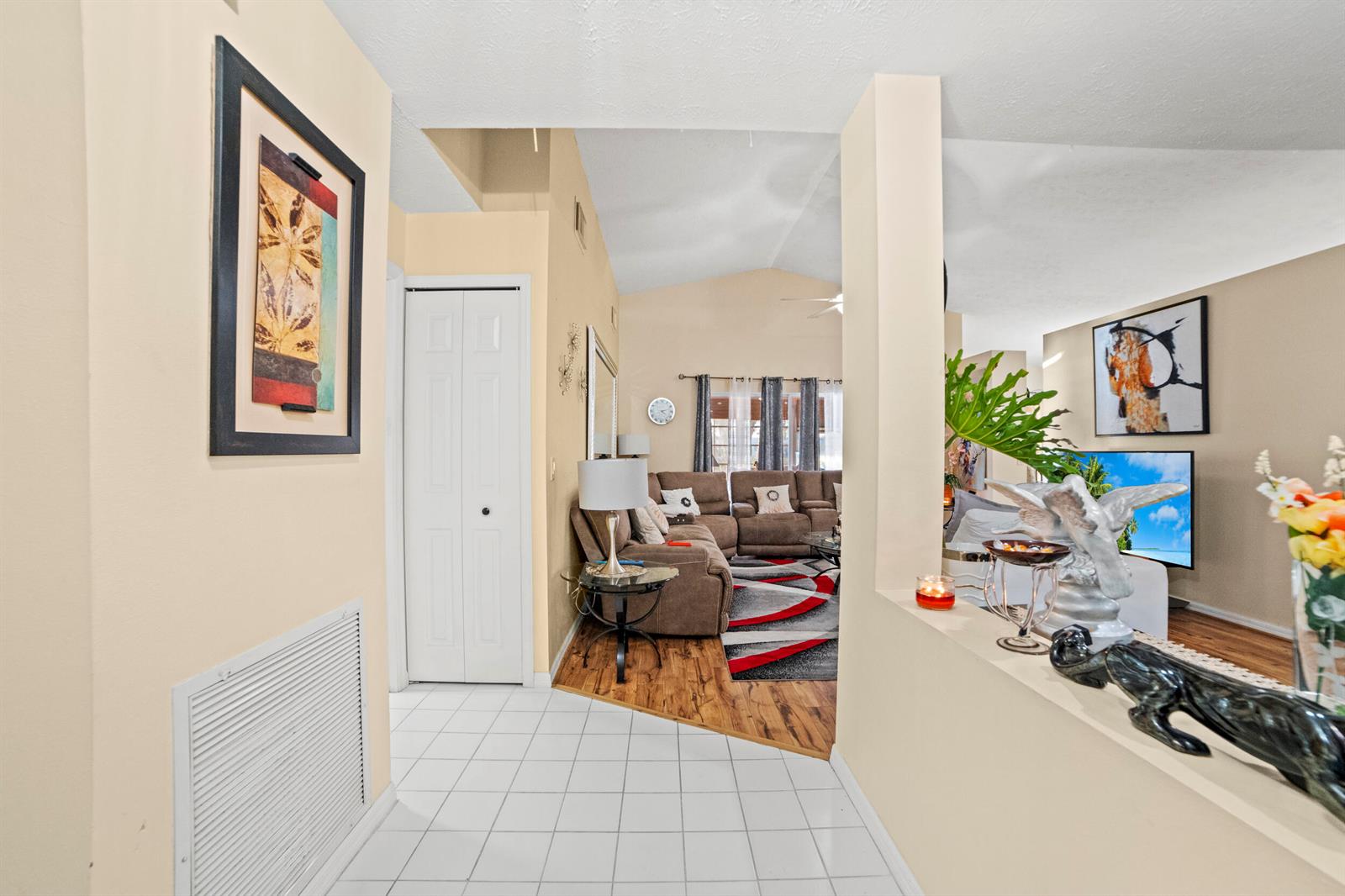 A tiled entryway leads into a living room with wood flooring and a vaulted ceiling — 14191 Cisne Circle, Fort Pierce FL 34951, FORT PIERCE, FL