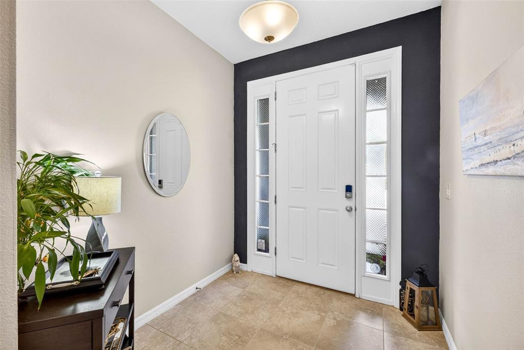 An entryway features a white front door with sidelights, a dark accent wall, and tile flooring — 2387 MIDNIGHT PEARL DRIVE, SARASOTA, FL
