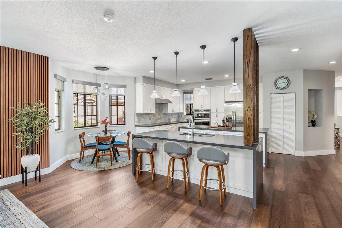 A modern kitchen features a large island with bar seating, white cabinetry, and wood accents — 2802 Kinsington Circle # 4, Weston FL 33332, WESTON, FL