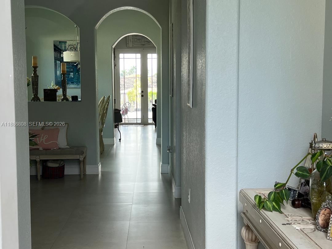A hallway with light tile flooring leads toward a glass-paned double door — 18247 NW 88th Pl, Hialeah FL 33018, HIALEAH, FL