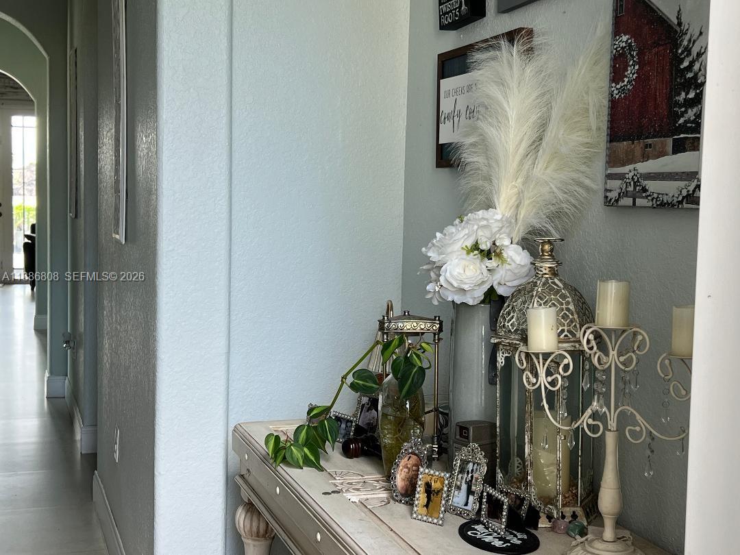 A hallway console table is decorated with flowers, candles, framed photos, and a plant — 18247 NW 88th Pl, Hialeah FL 33018, HIALEAH, FL
