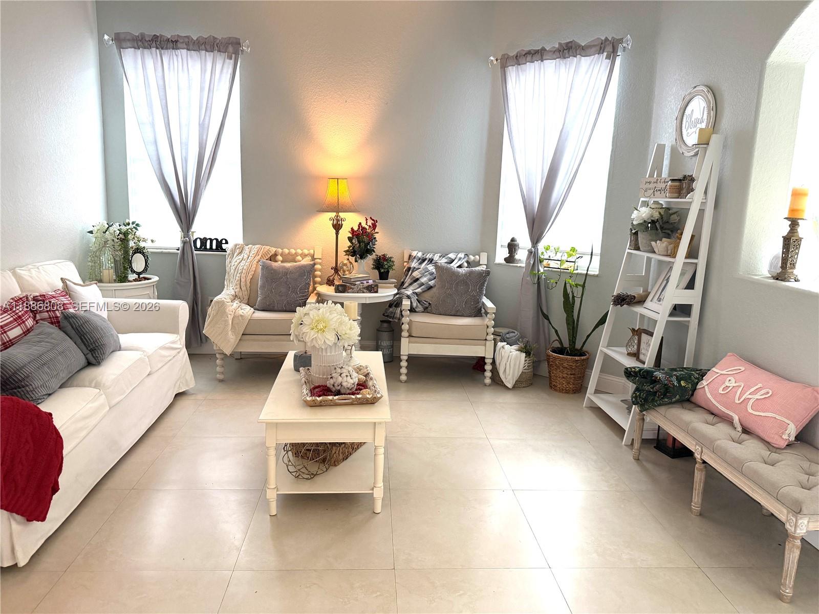 A bright living room features white furniture, a coffee table, and a decorative ladder shelf — 18247 NW 88th Pl, Hialeah FL 33018, HIALEAH, FL