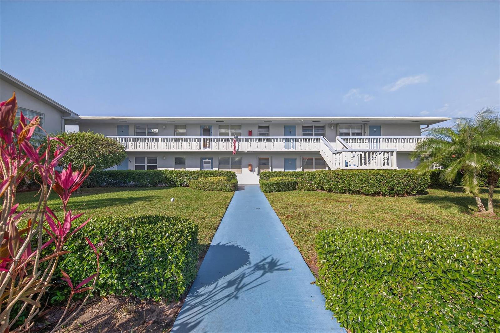 A two-story apartment building with a blue walkway leading to the entrance — 51 Farnham C, Deerfield Beach FL 33442, DEERFIELD BEACH, FL
