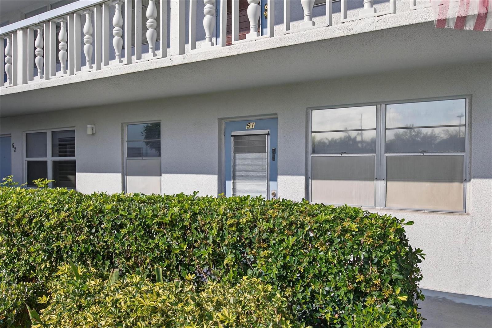An exterior view of a ground-floor apartment unit with a blue door numbered 51 — 51 Farnham C, Deerfield Beach FL 33442, DEERFIELD BEACH, FL
