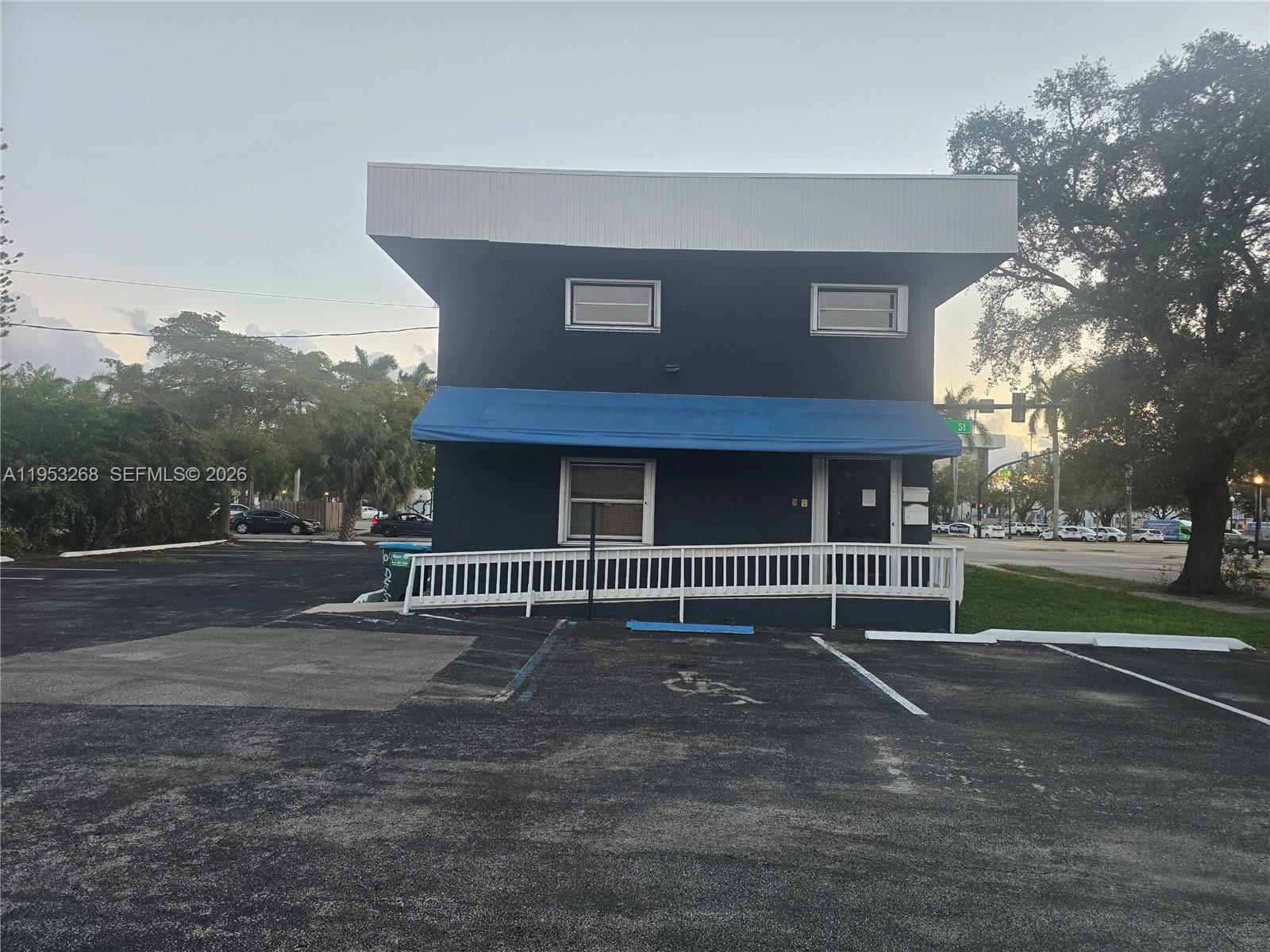 A two-story dark blue commercial building features a blue awning and a white wheelchair ramp — 2555 Polk St, Hollywood FL 33020, HOLLYWOOD, FL