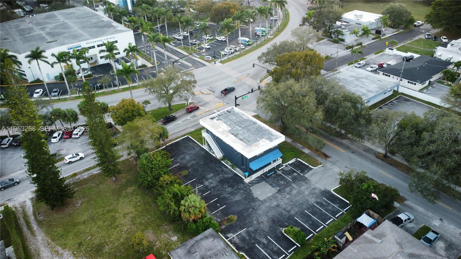 An aerial view shows a commercial building with a parking lot at a street intersection — 2555 Polk St, Hollywood FL 33020, HOLLYWOOD, FL