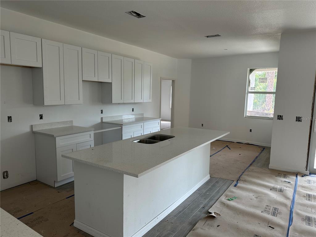 A kitchen under construction features white cabinets, a quartz-topped island, and unfinished flooring — 5462 GAGNON TERRACE, NORTH PORT, FL