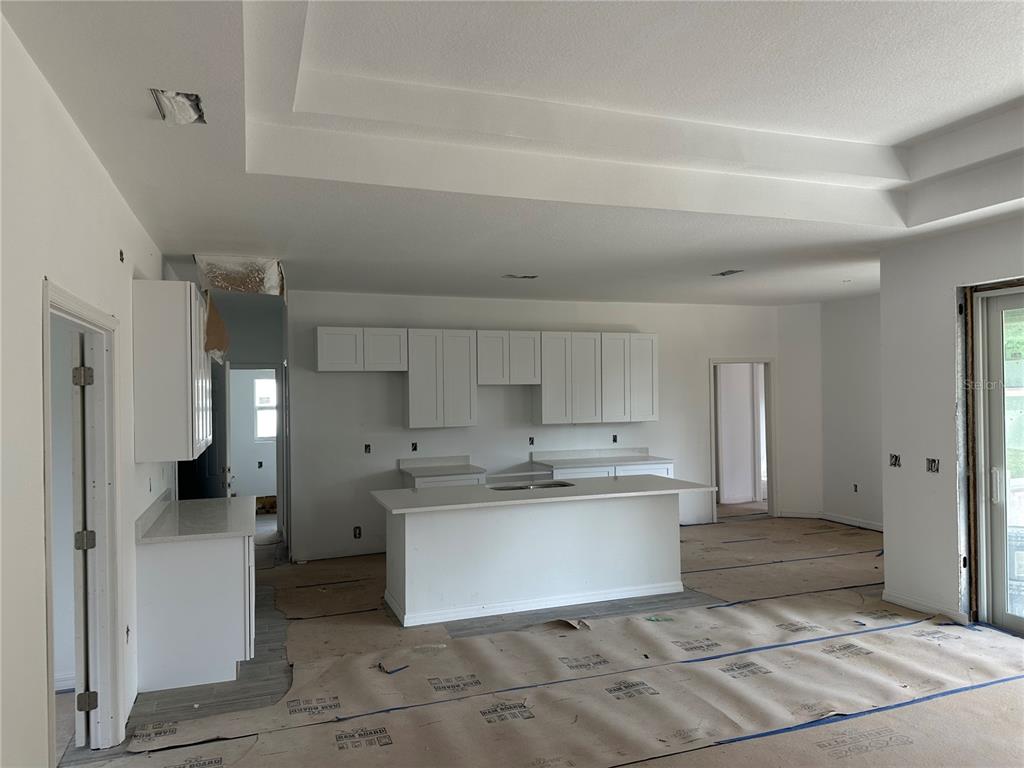 An unfinished kitchen features white cabinets, a central island with a sink, and protective floor covering — 5462 GAGNON TERRACE, NORTH PORT, FL