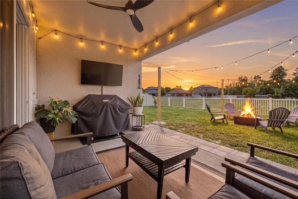 A covered patio features outdoor seating, a grill, a television, and a backyard fire pit — 13471 NEWPORT SHORES DRIVE, HUDSON, FL