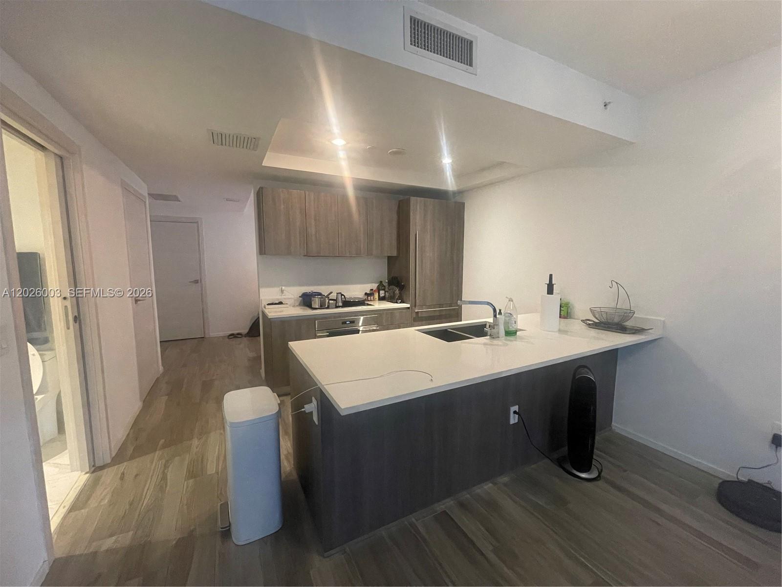 A modern kitchen features dark wood cabinetry, white countertops, and a central island — 801 S Miami Ave # 2207, Miami FL 33130, MIAMI, FL