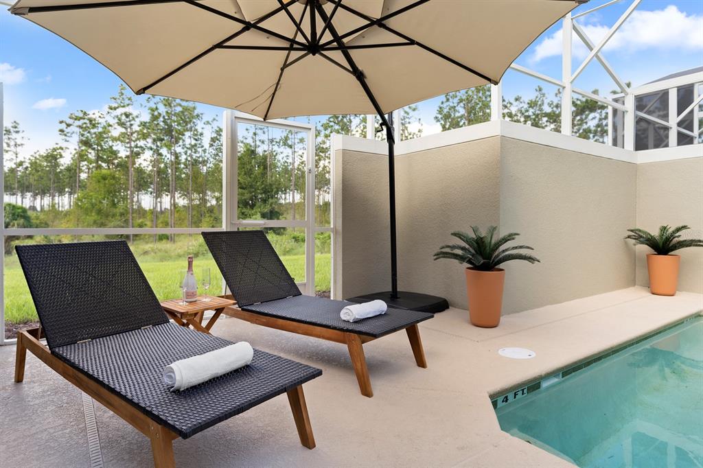 Two lounge chairs with towels sit on a pool deck under an umbrella — 278 OCEAN COURSE AVENUE, DAVENPORT, FL