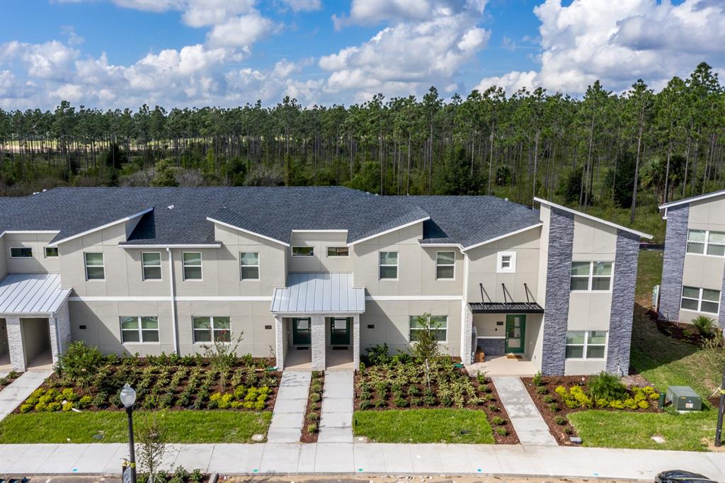 An exterior view of a multi-unit townhouse building with gray siding, stone accents, and landscaping — 278 OCEAN COURSE AVENUE, DAVENPORT, FL