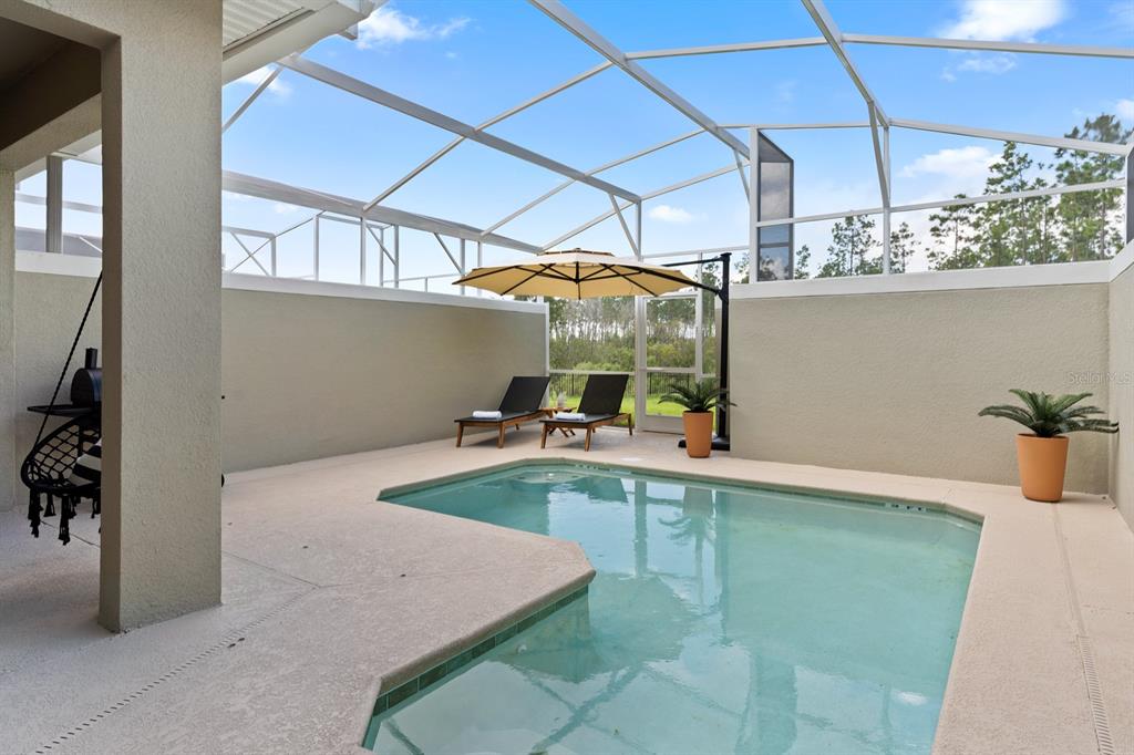 A screened-in patio features a small swimming pool, two lounge chairs, and an umbrella — 278 OCEAN COURSE AVENUE, DAVENPORT, FL