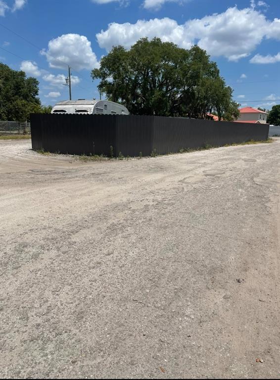 A dark metal privacy fence encloses a lot with a trailer and large tree — 6009 MCKINLEY AVENUE, WIMAUMA, FL