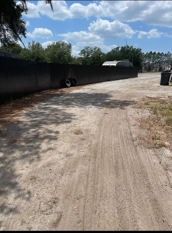 A dirt driveway runs alongside a long, dark metal fence under a blue sky — 6009 MCKINLEY AVENUE, WIMAUMA, FL