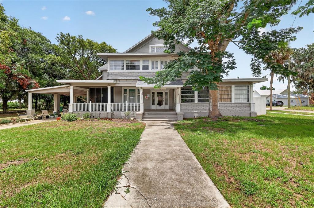 A two-story gray house with a large front porch and a concrete walkway — 527 E LEMON AVENUE, EUSTIS, FL