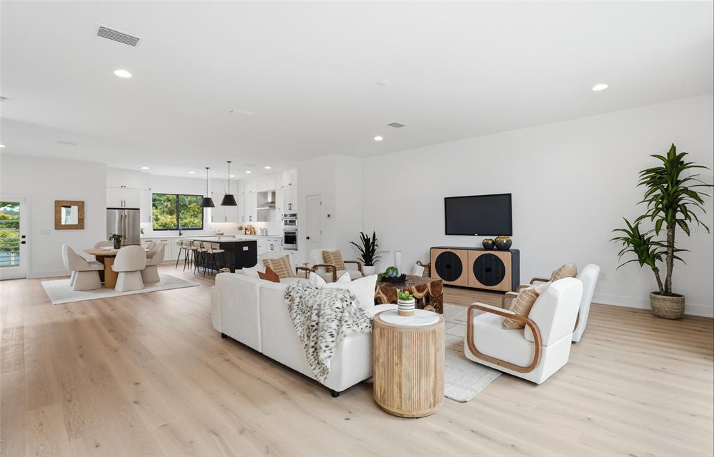An open-concept living room and kitchen feature white walls, light wood floors, and modern furniture — 3002 W PLATT UNIT 3, TAMPA, FL