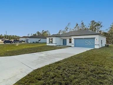 A single-story house with a white exterior, a blue garage door, and a concrete driveway — 13195 SW 67TH AVENUE, OCALA, FL